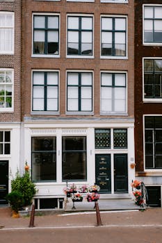 A stylish townhouse facade in an urban setting, decorated with colorful flowers and classic architecture.
