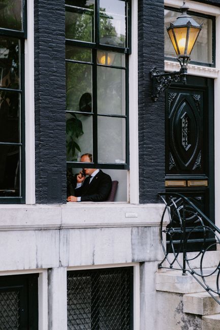 A businessman in Amsterdam is seen through a window, gazing thoughtfully outside.