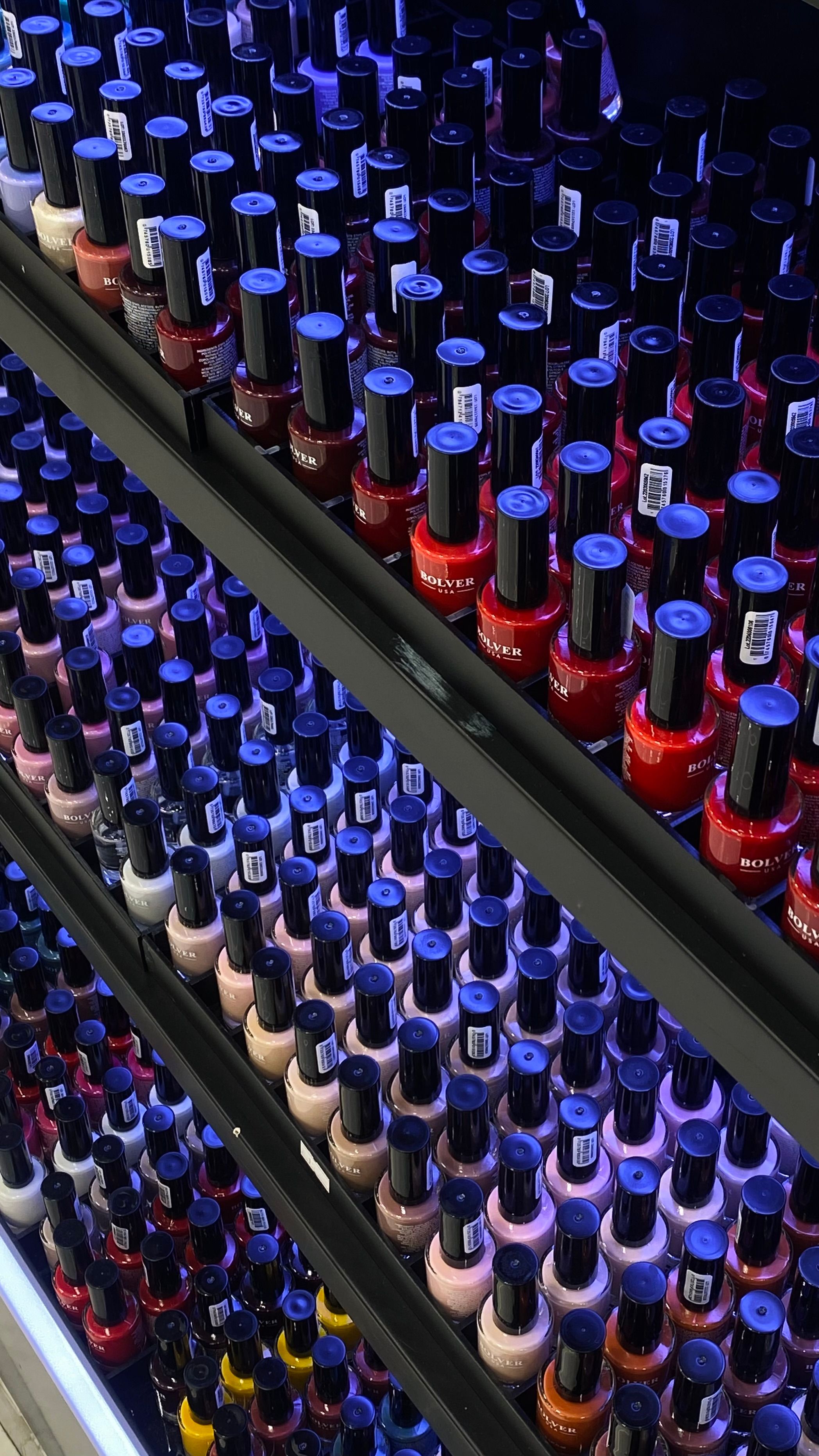 Colorful assortment of nail polish bottles displayed neatly on store shelves, offering a variety of choices.