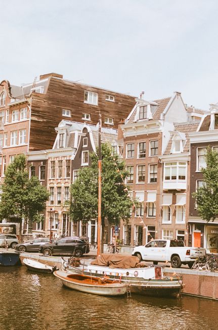 Scenic view of Amsterdam canal with traditional Dutch buildings and moored boats, perfect for travel inspiration.