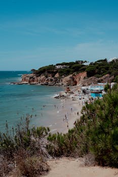 A beautiful beach in Algarve, Portugal with clear blue waters and cliffs, perfect for a summer getaway.