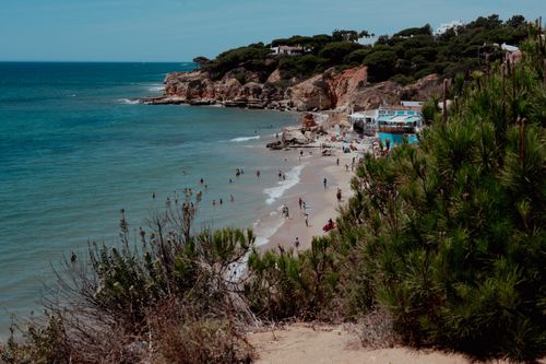 Free A picturesque view of the Algarve coastline featuring a sandy beach and clear blue ocean, perfect for a summer getaway. Stock Photo