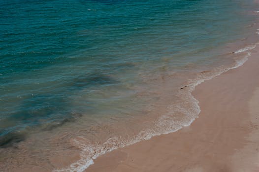 Calm beach with gentle turquoise waves lapping onto sandy shore, perfect for summer travel inspiration.