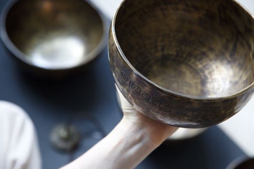 Detailed shot of an intricately designed singing bowl being held in hand, focus on texture.