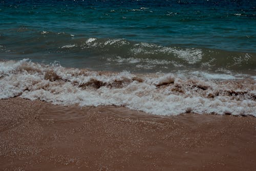 A person standing on the beach with the ocean waves