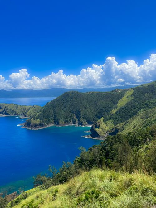 Free Breathtaking view of the coast with vibrant blue sea and lush green hills under a clear sky. Stock Photo