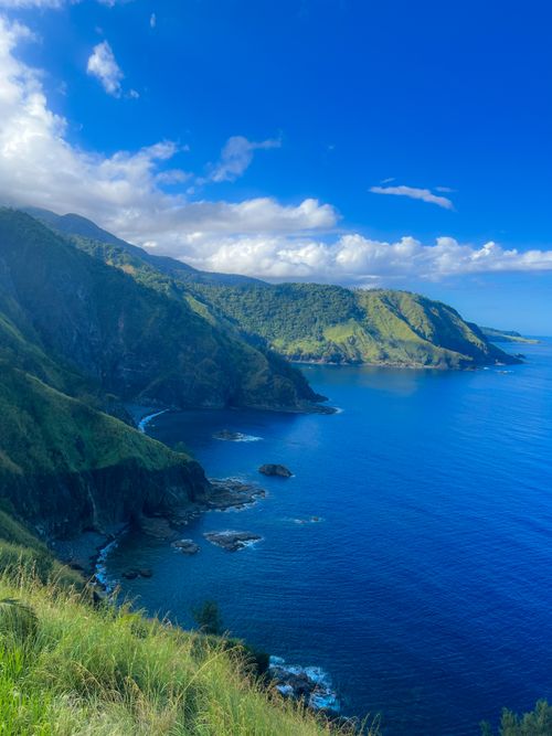 Free Stunning aerial view of lush green cliffs and blue sea under a vibrant sky. Stock Photo