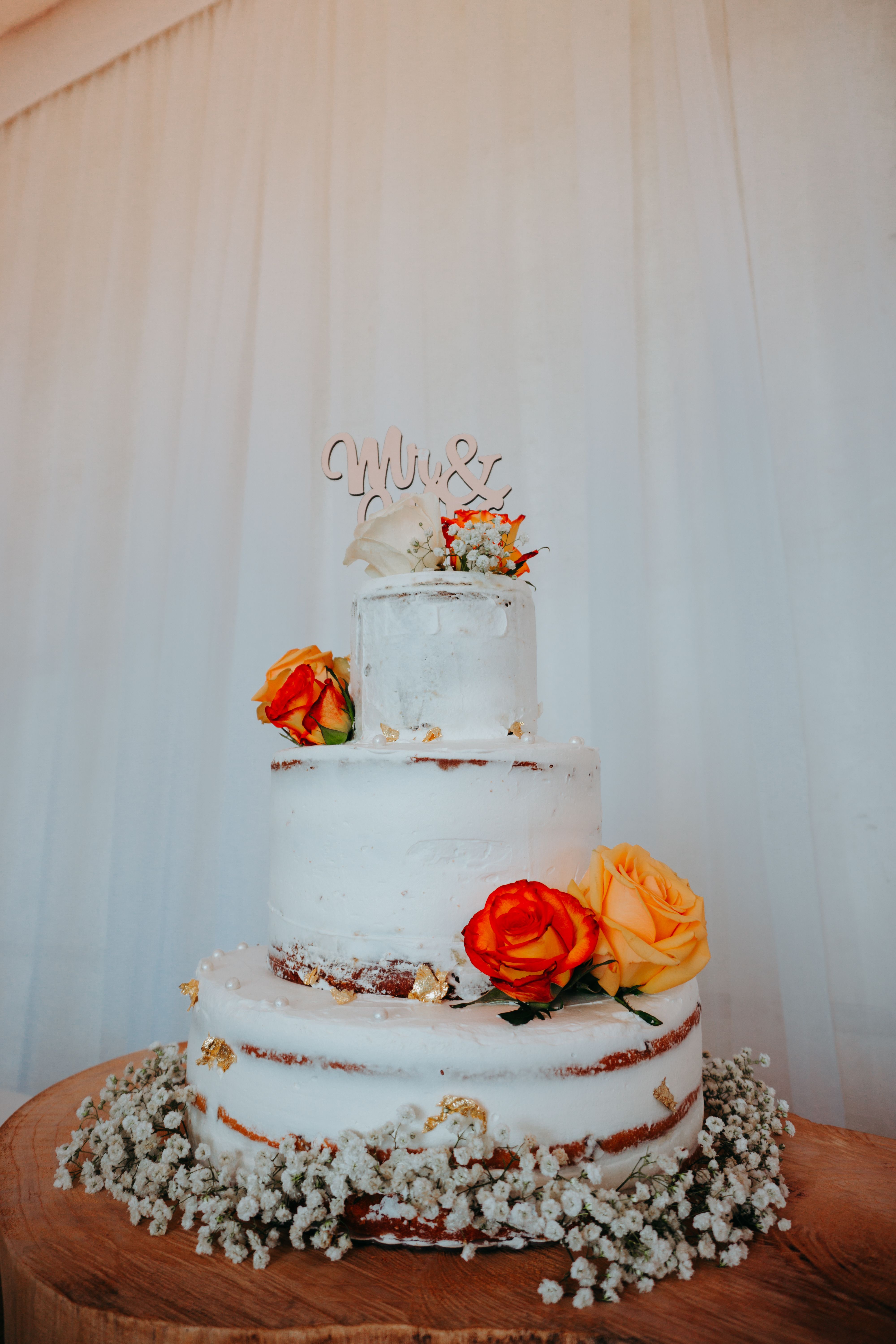 Three-tier wedding cake with roses and baby's breath for a perfect celebration.