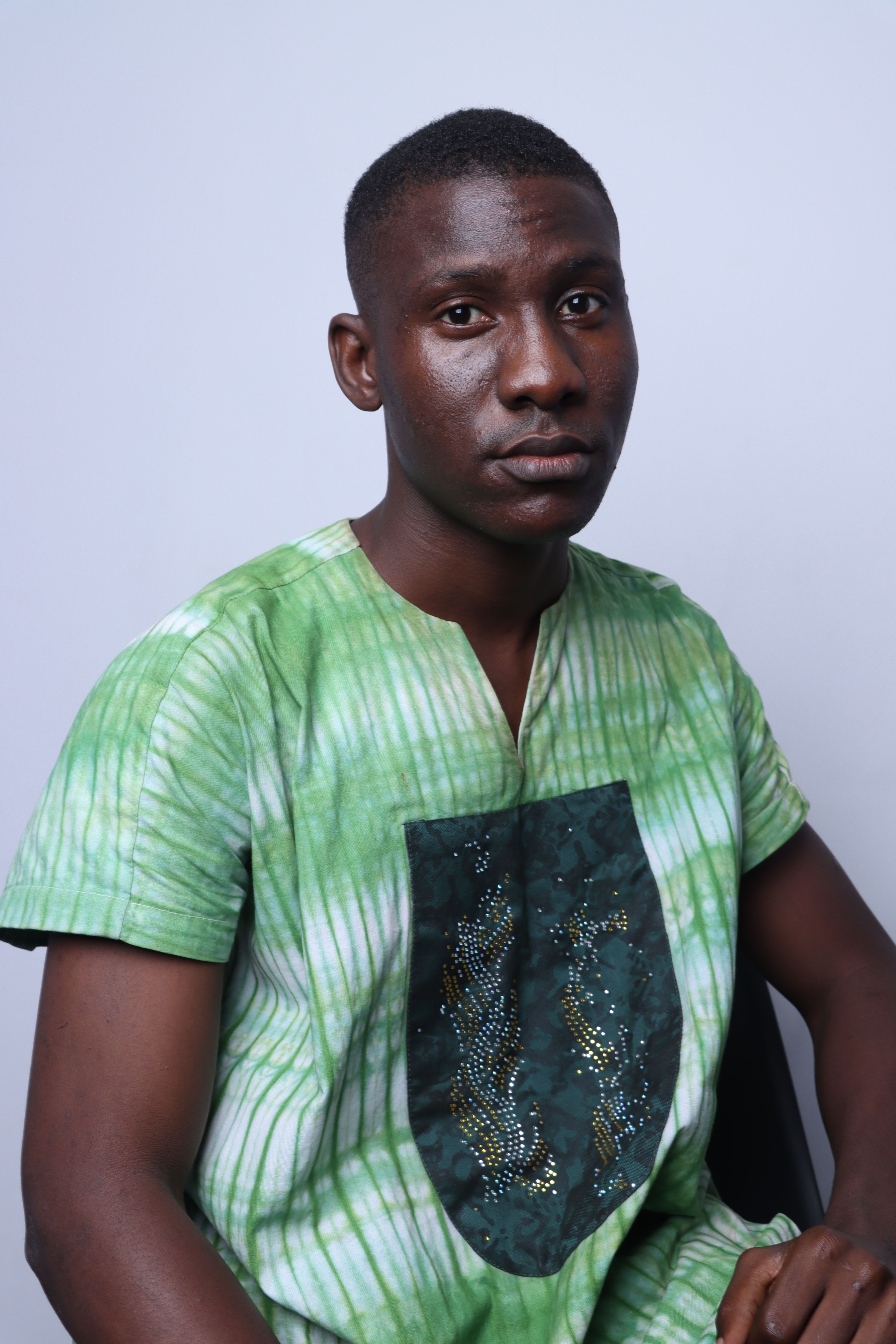 Studio portrait of an African man in green traditional clothing posing confidently.
