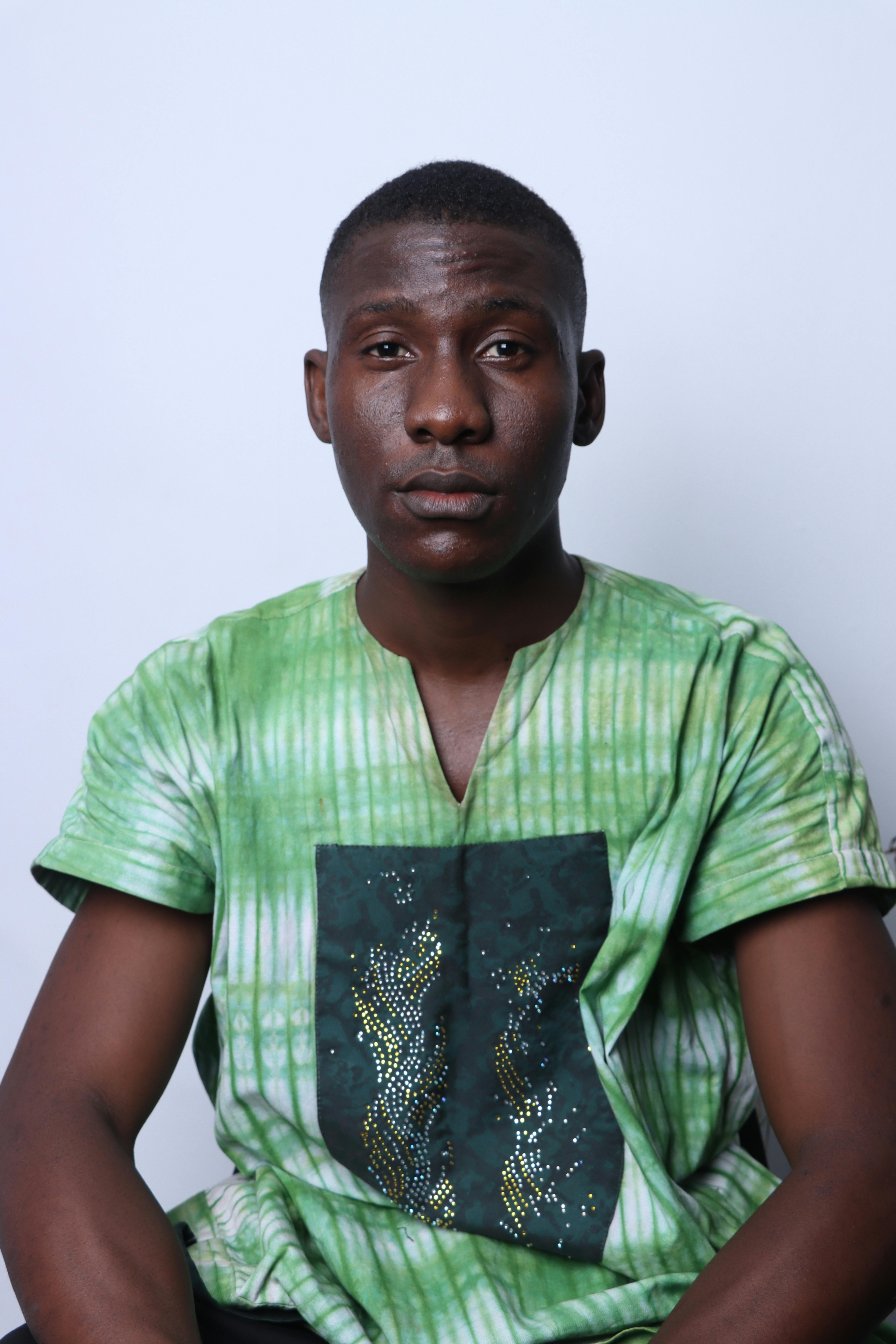 A confident man in a traditional green shirt poses against a plain backdrop.