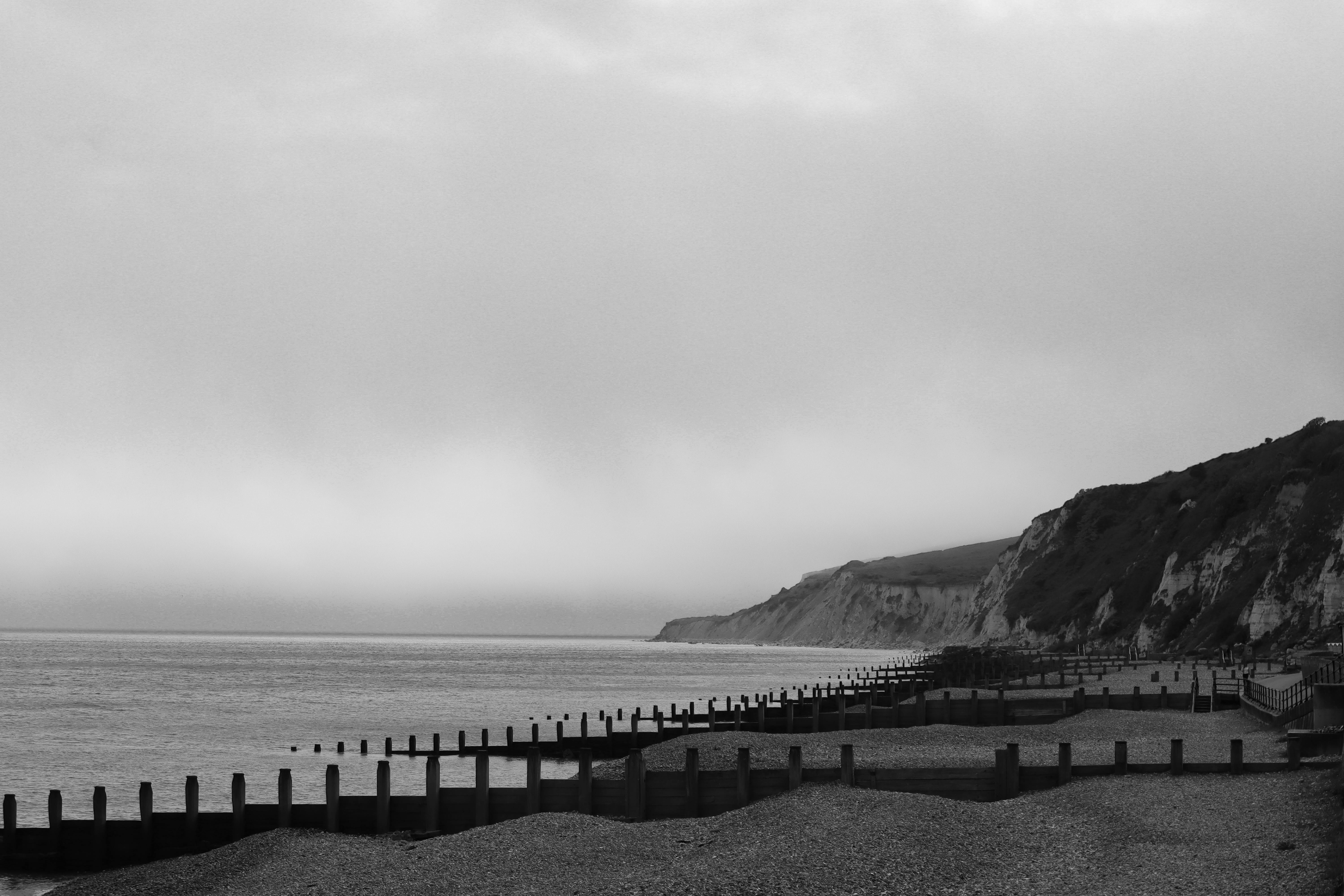 Peaceful black and white landscape of Eastbourne coast with cliffs and pebbled beach.