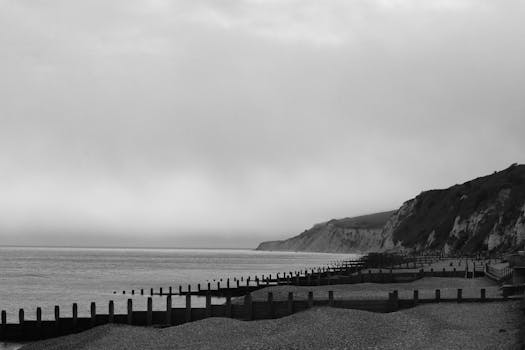 Peaceful black and white landscape of Eastbourne coast with cliffs and pebbled beach.