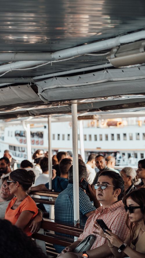 Free View of diverse passengers aboard a ferry on a sunny day, showcasing travel and transit. Stock Photo