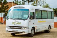 A white tourist bus with TemberuRwanda branding parked outdoors in Rwanda.