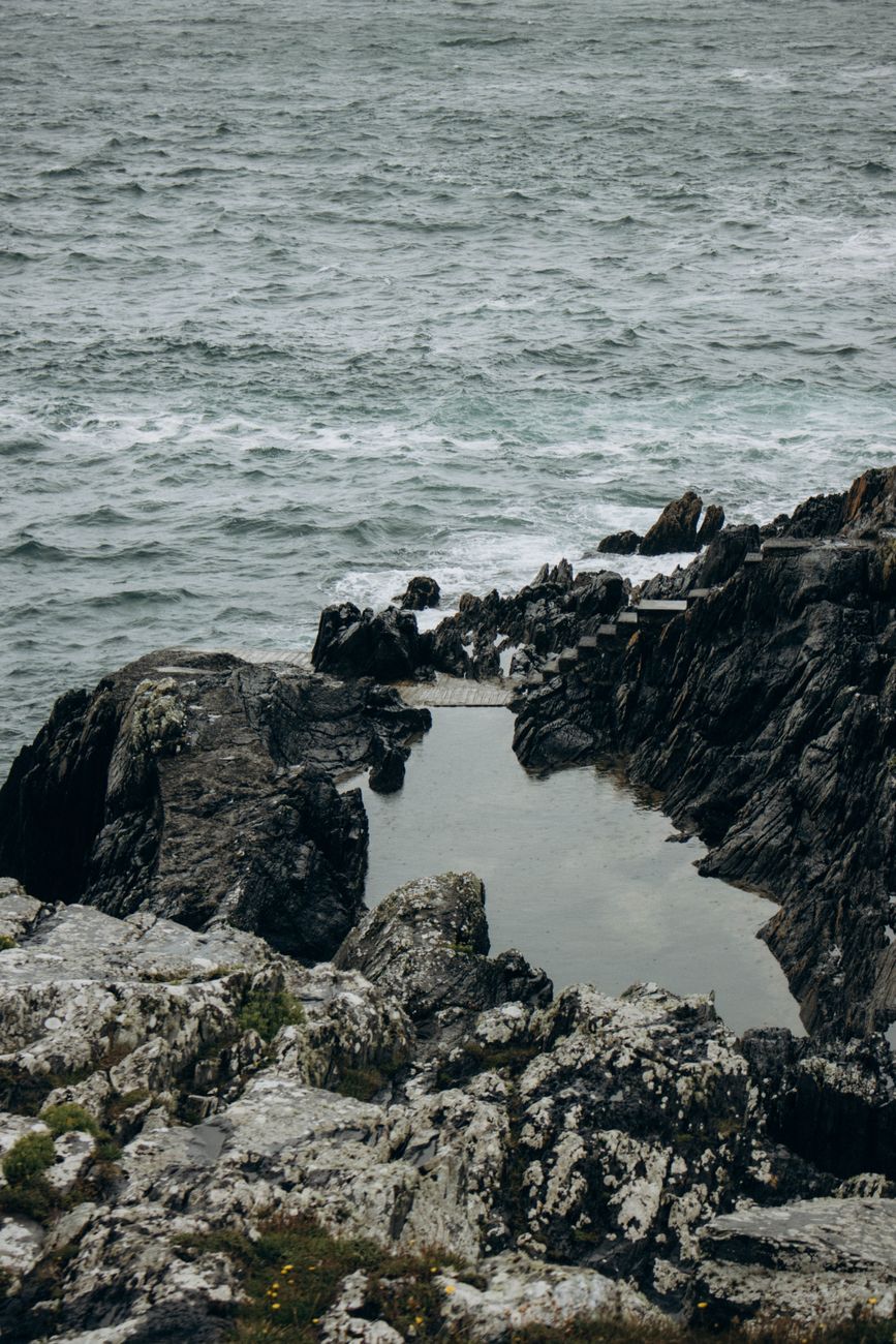 A dramatic rocky seashore with a tide pool reflecting the overcast sky.. dramatic, rocky, seashore