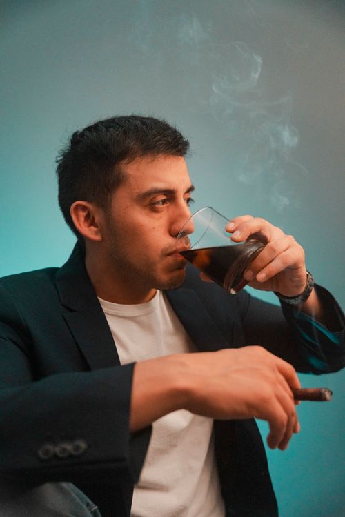 Free Young man in a suit smoking a cigar and drinking cola indoors, Chicago. Stock Photo