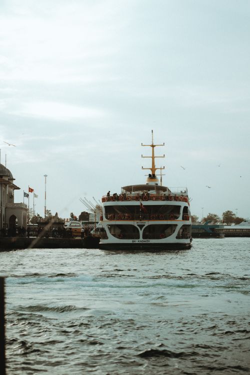 Free A bustling ferry navigates through a vibrant harbor surrounded by calm sea. Stock Photo