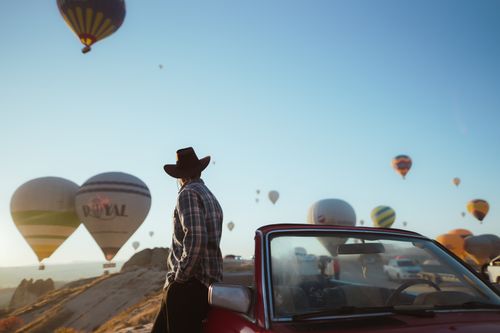 Free Man enjoying hot air balloons at sunrise in Cappadocia, Turkey, with clear skies and scenic views. Stock Photo