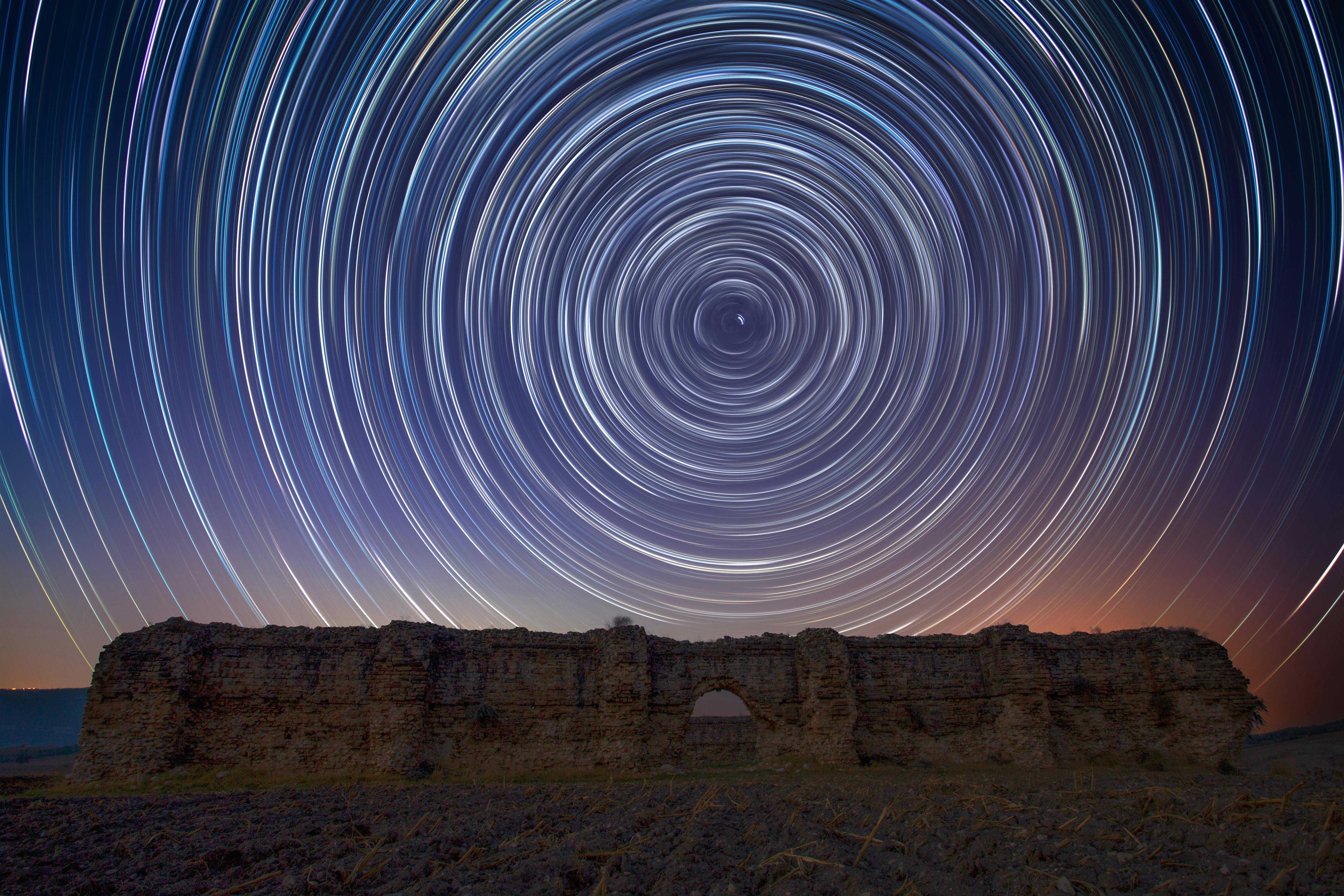 Vibrant star trails swirl over ancient ruins in Karaisalı, Adana, creating a mesmerizing cosmic display.