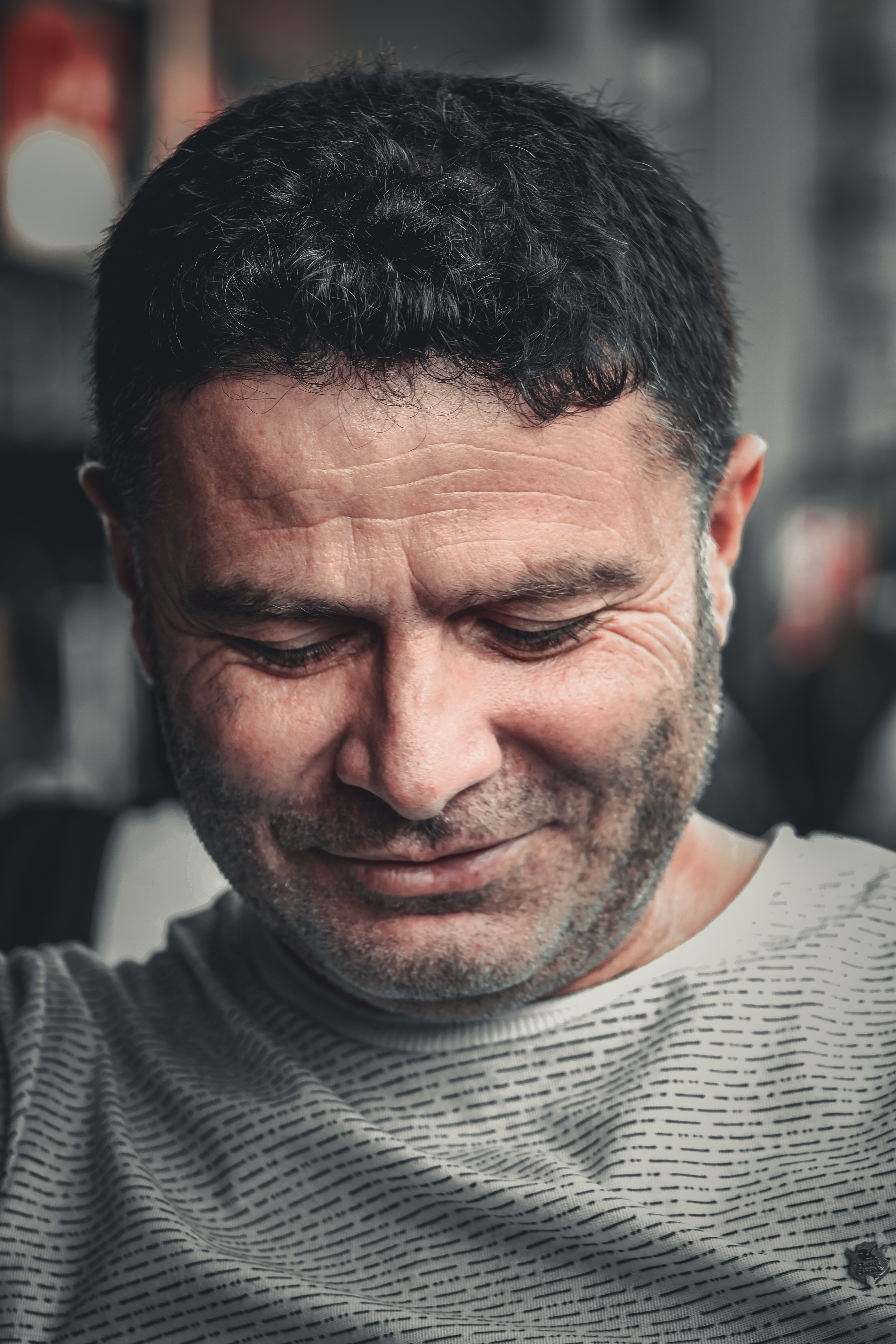Close-up portrait of a content man looking down and smiling naturally, evoking warmth and introspection.