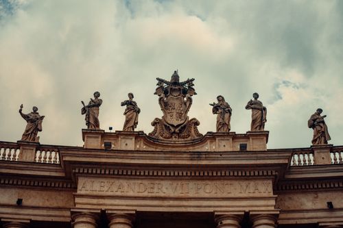 Free Intricate statues atop Vatican architecture under a cloudy sky, capturing religious artistry. Stock Photo