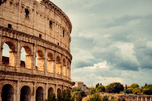 Free Stunning view of the iconic Colosseum in Rome under dramatic cloudy skies. Stock Photo