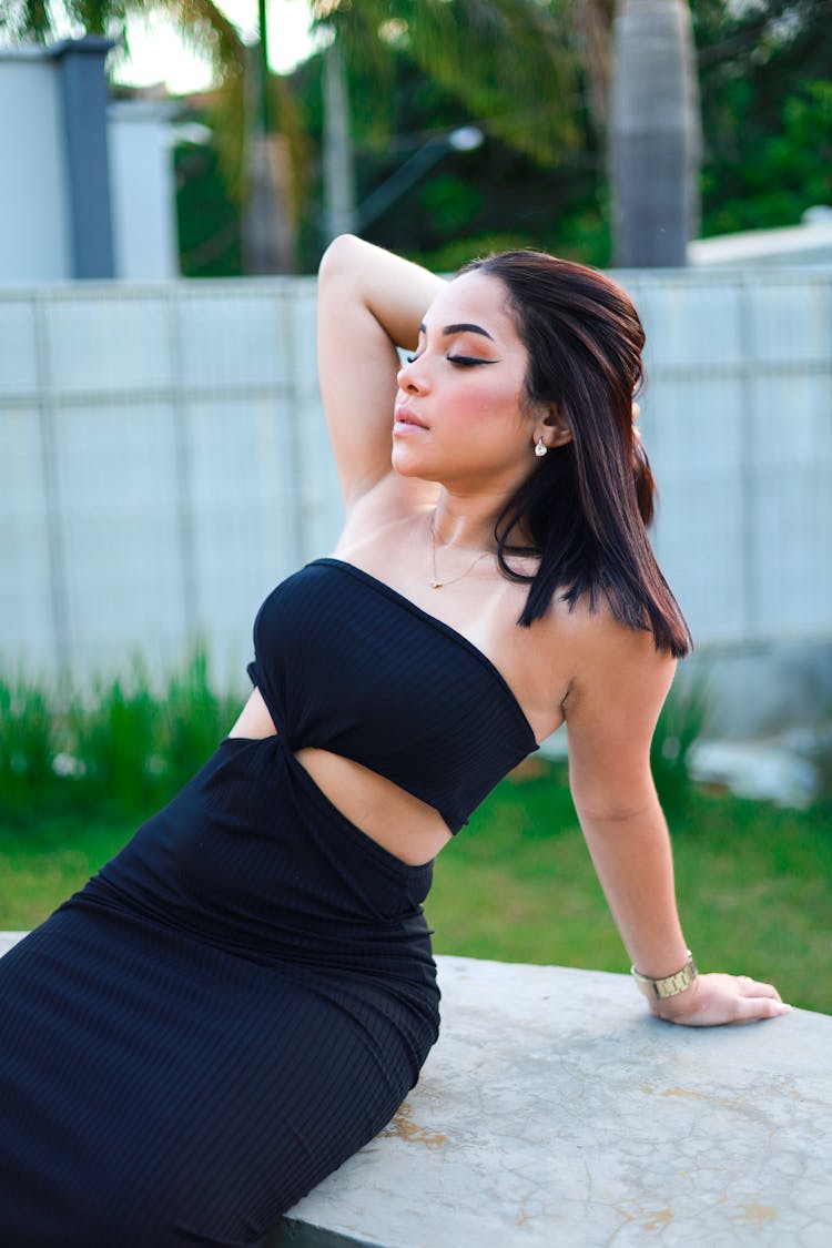 Woman In Black Strapless Dress Sitting On Stone