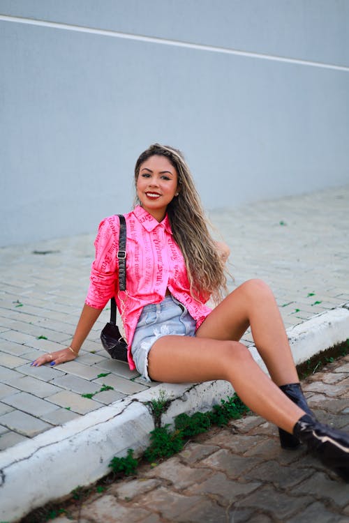 Young Woman Sitting on a Curb and Smiling 
