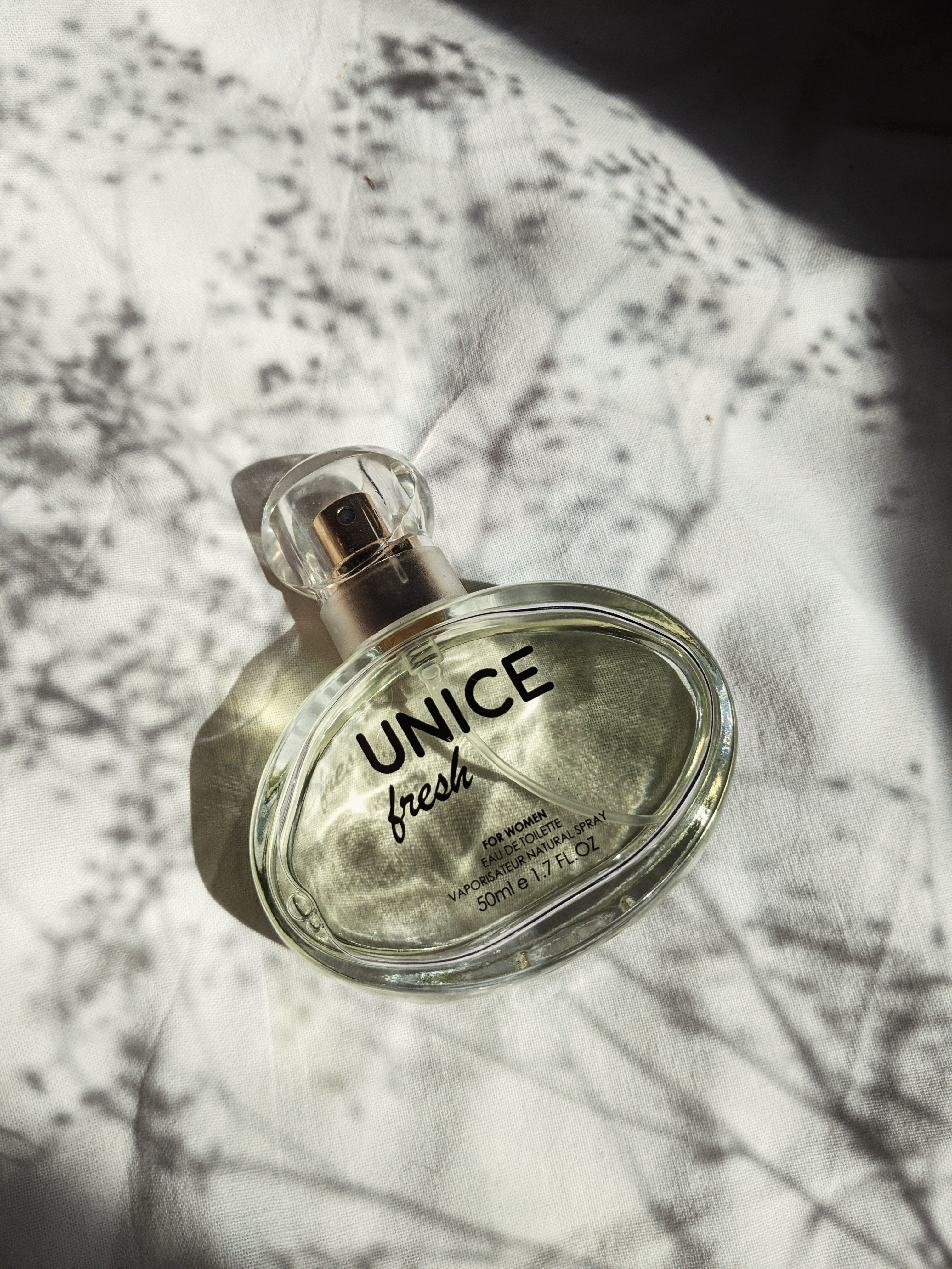 Stylish Unice perfume bottle captured in soft artistic lighting with shadow play.
