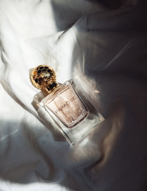 A Bottle of Perfume Lying on a White Sheet 