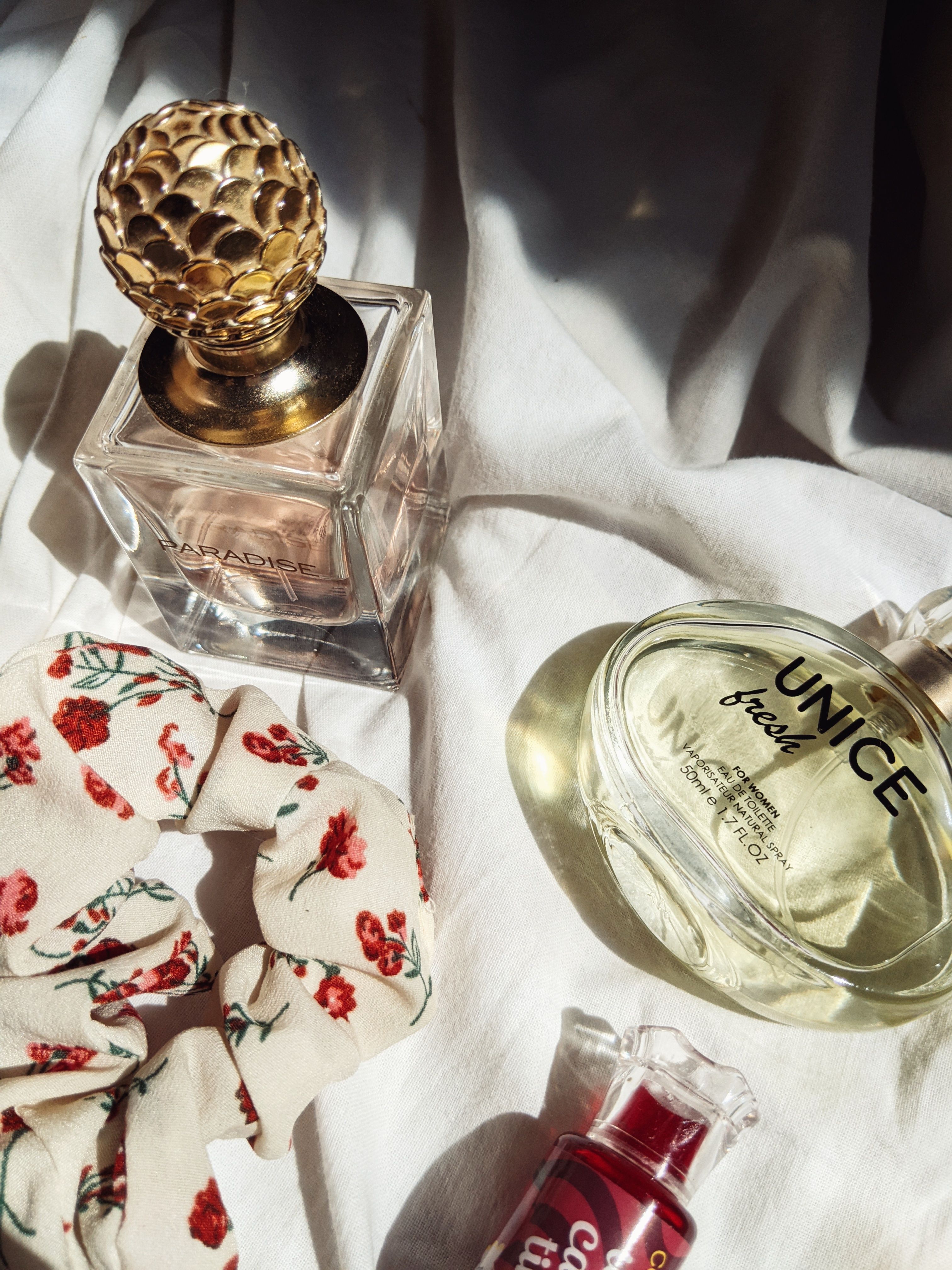 A stylish arrangement of luxury perfume bottles and accessories on a soft fabric background.