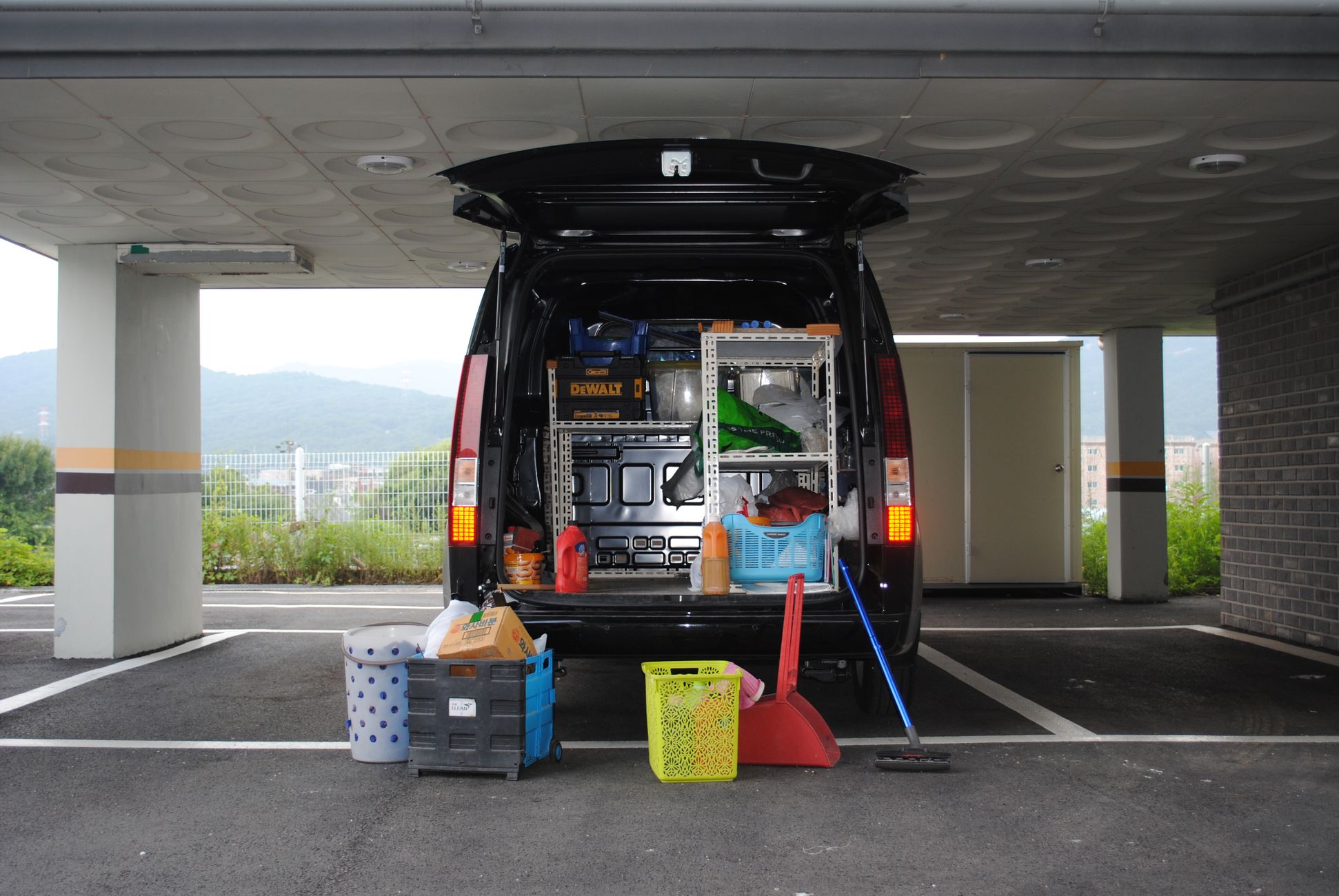 Back view of a black van with equipment in an urban parking area.