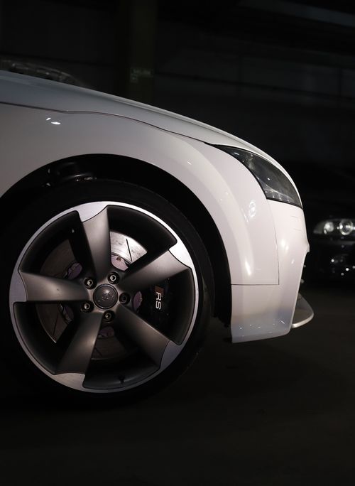 Free Detailed shot of a white sports car wheel in a dimly lit setting, highlighting modern design. Stock Photo