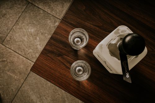 Free Minimalist top view of two empty glasses and a bottle on a wooden table surface. Stock Photo