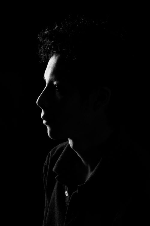Free Dramatic side profile of a young man artistically lit in black and white. Stock Photo
