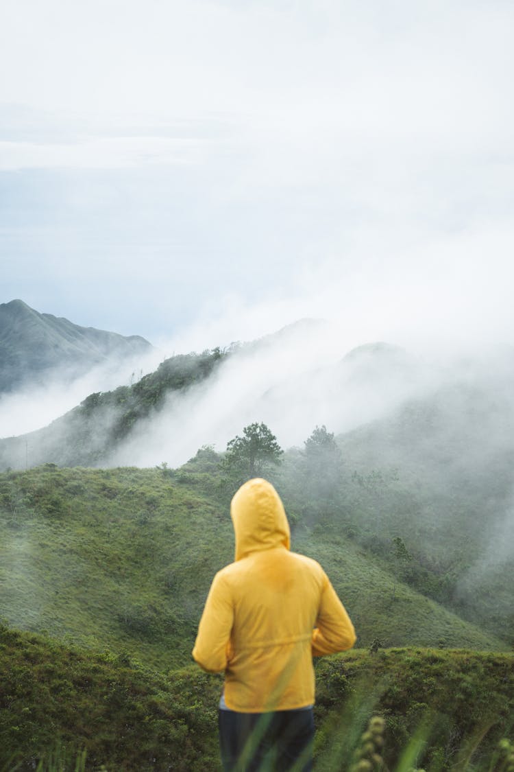 Person In Yellow Jacket Hiking On Hills