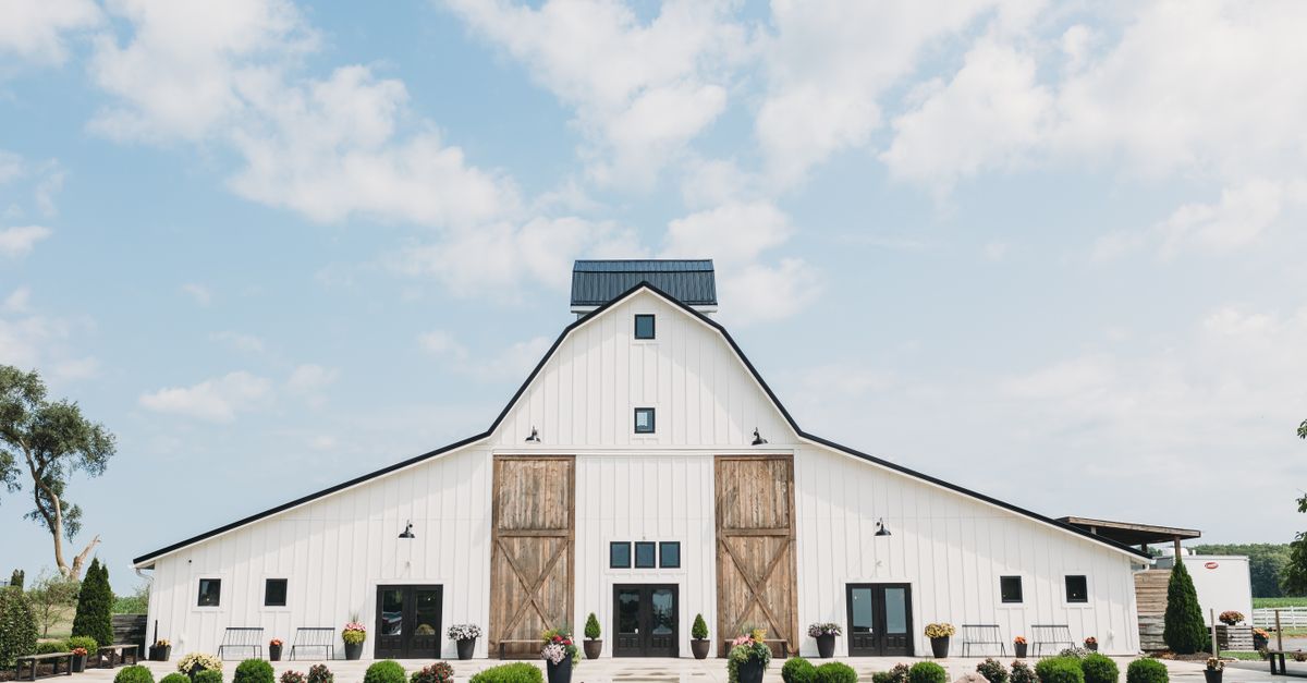 Charming white barn under a clear blue sky, perfect for rustic weddings or countryside themed events.