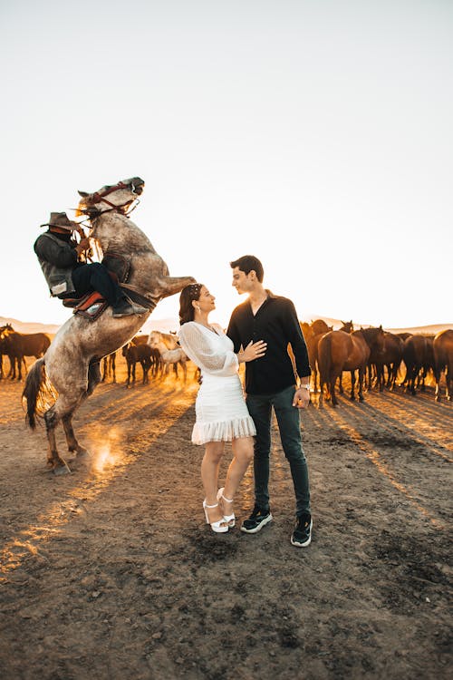 Couple Standing next to a Man on a Horse 