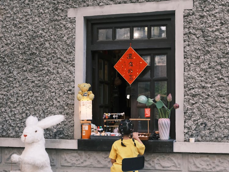 Little Girl Buying At Window In Small Shop 