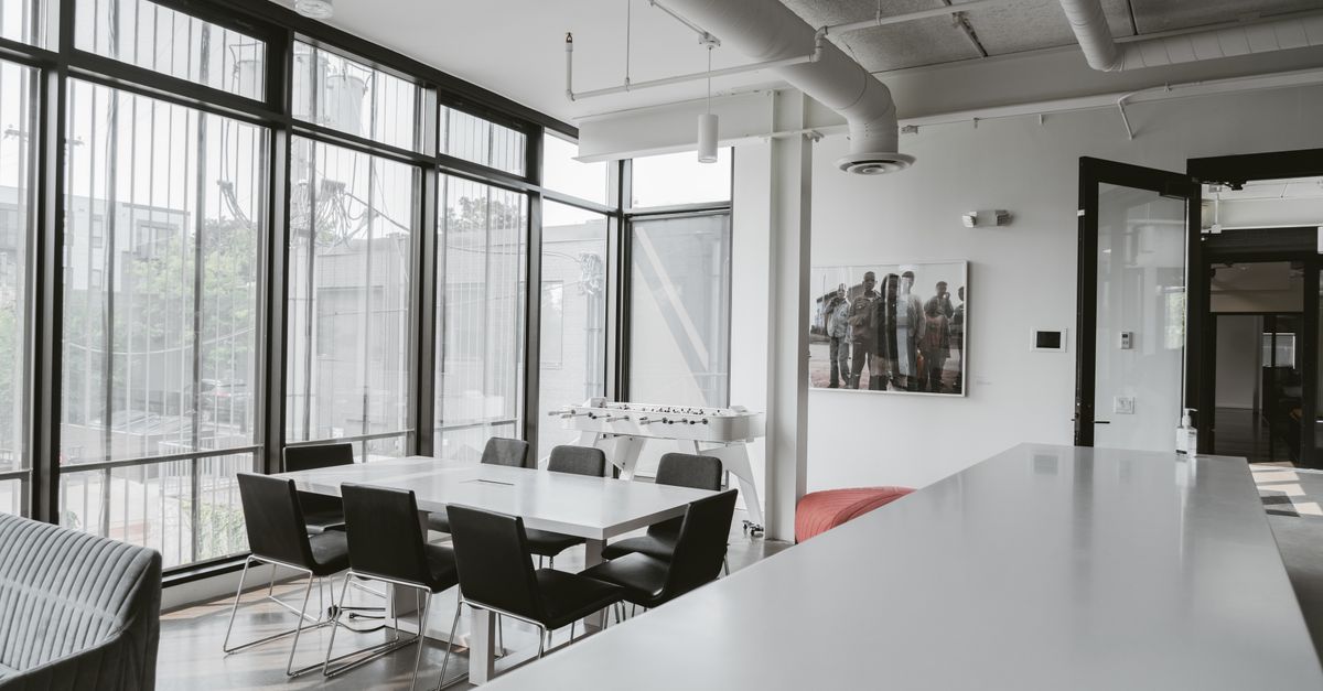 Bright and airy modern office space featuring a large conference table and sleek design elements.