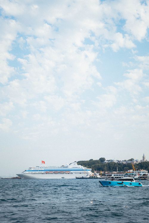 Free A serene view of a cruise ship and boats in a bustling harbor under a cloudy sky. Stock Photo