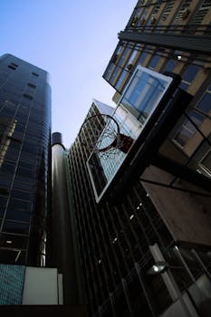 Low angle view of a basketball hoop against skyscrapers in a city setting.