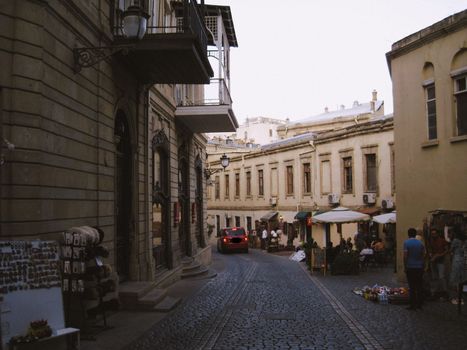 Quaint cobblestone street scene in Baku with historic architecture and lively market atmosphere.