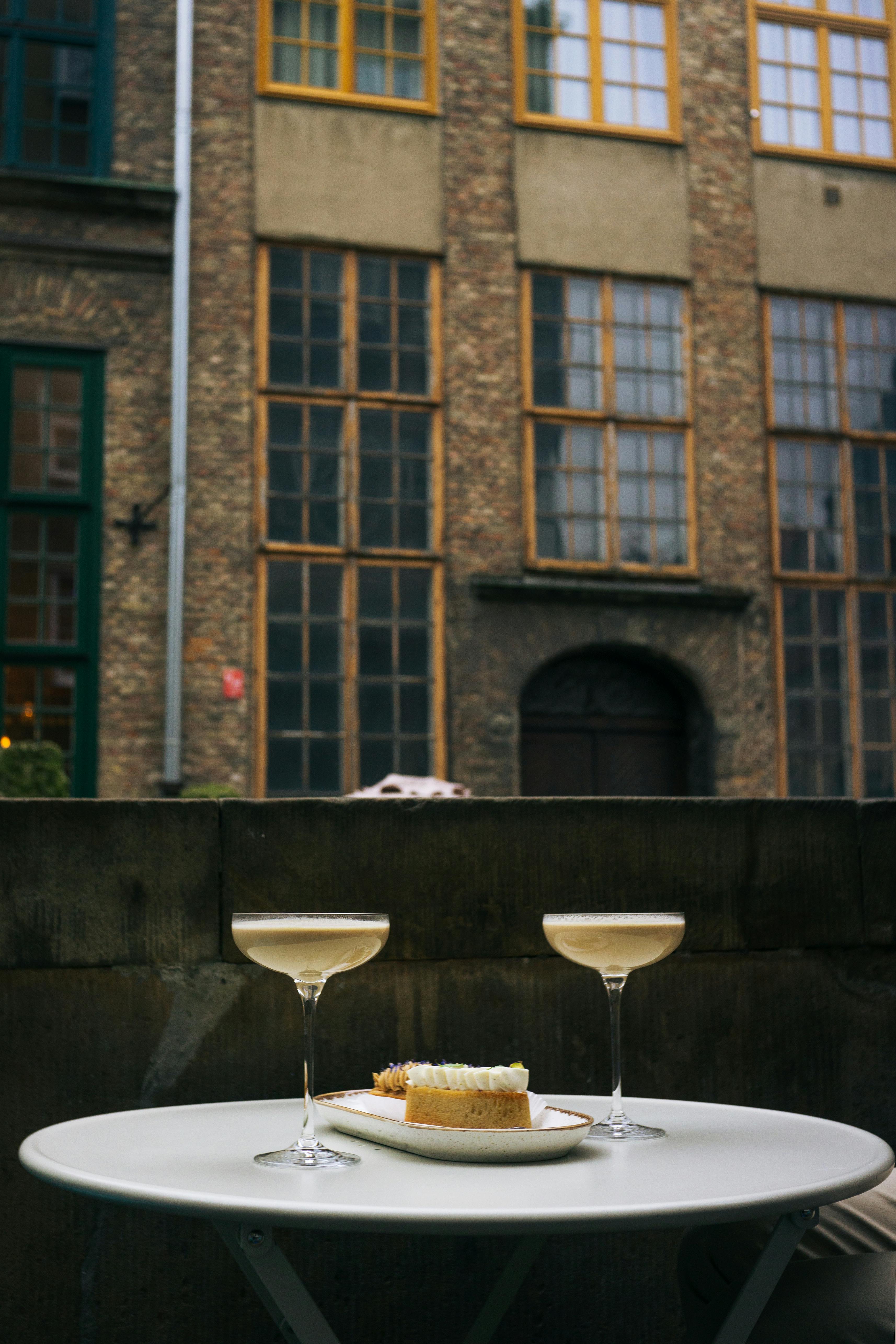 Outdoor café table with champagne and cake in a city setting.