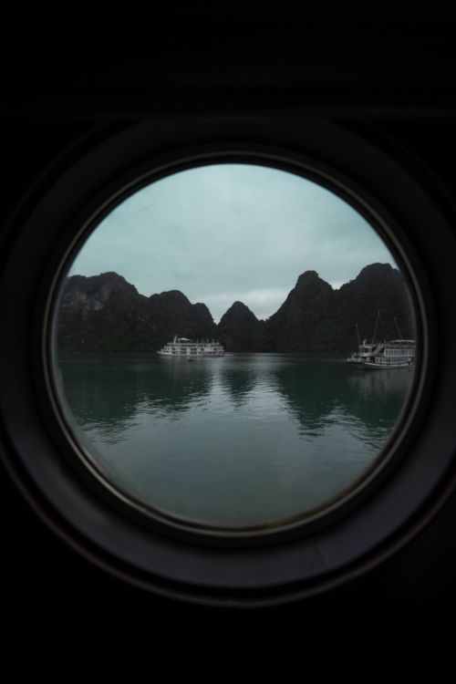 Free A tranquil view of boats on calm water framed by a round window. Stock Photo