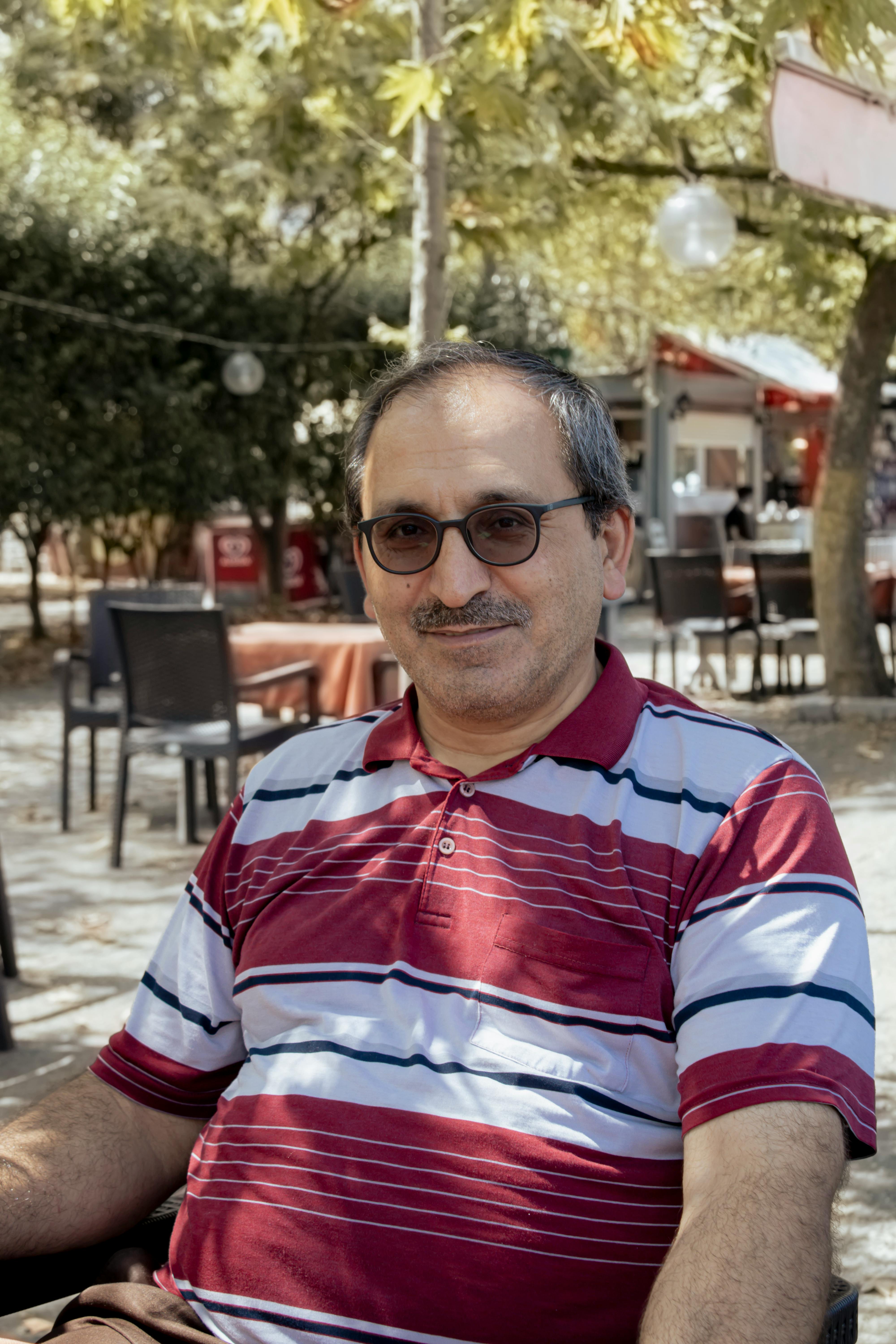 Smiling man with sunglasses outdoors in a casual setting.