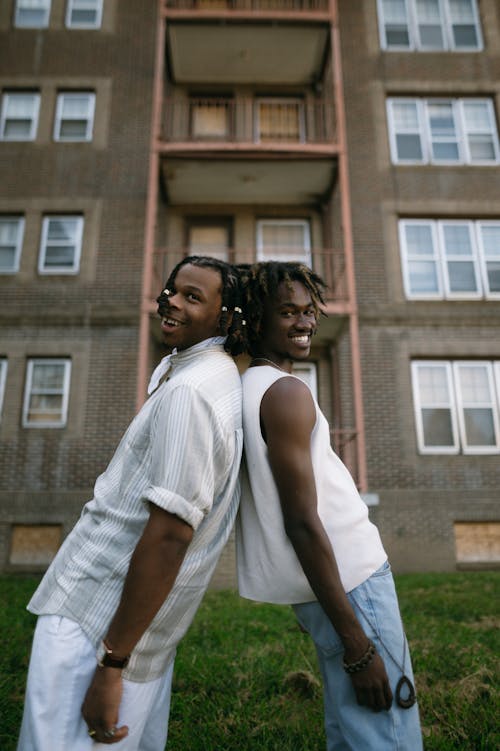 Two Young Men Standing Back to Back and Smiling 