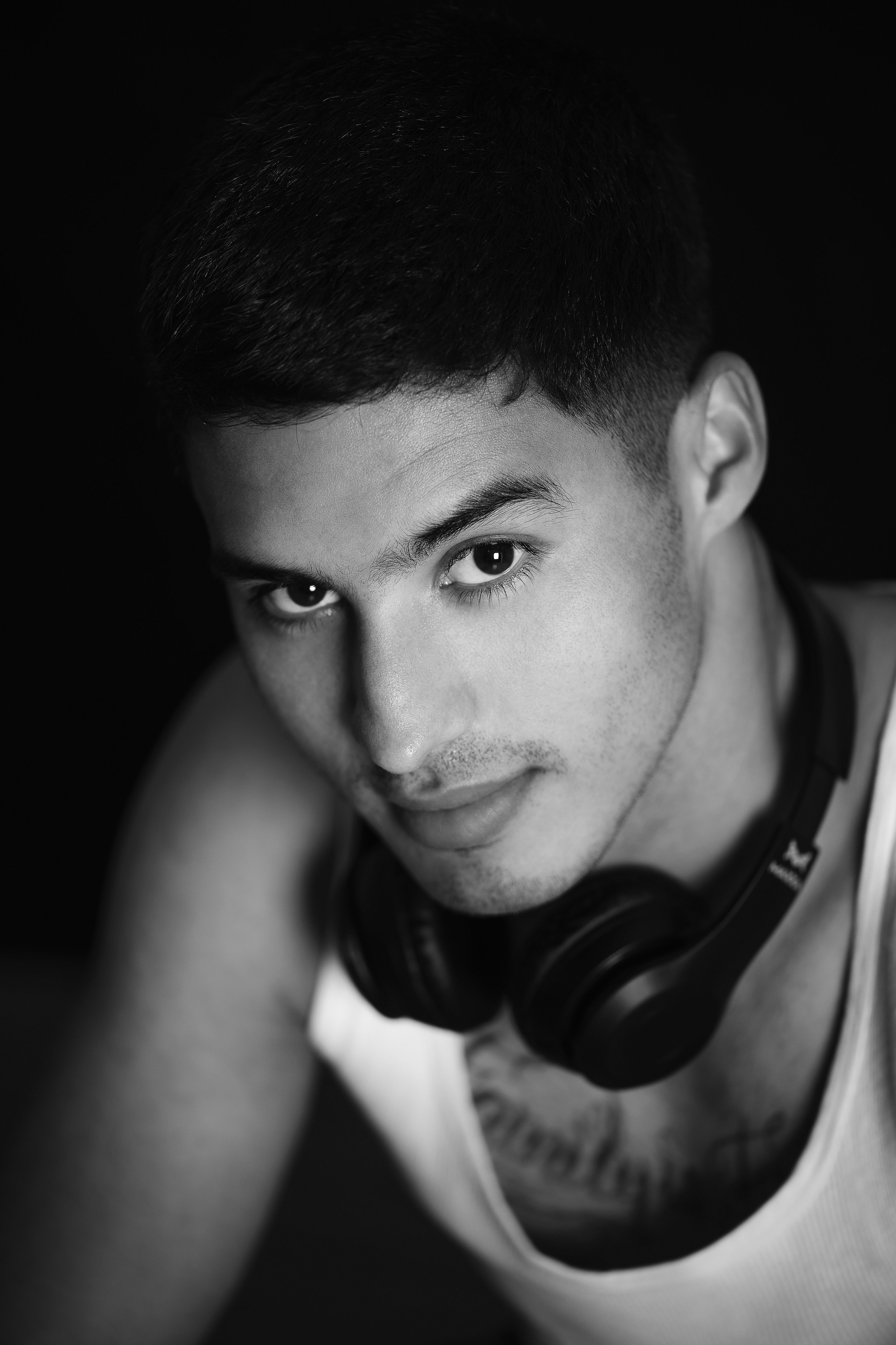 Black and white portrait of a young man wearing headphones and a tank top.