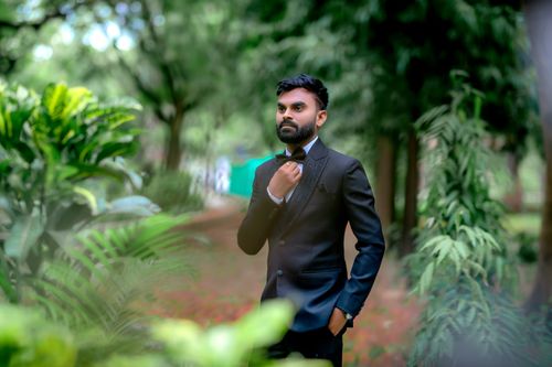 Free Elegant portrait of an Indian man in a tuxedo set against a lush outdoor backdrop. Stock Photo