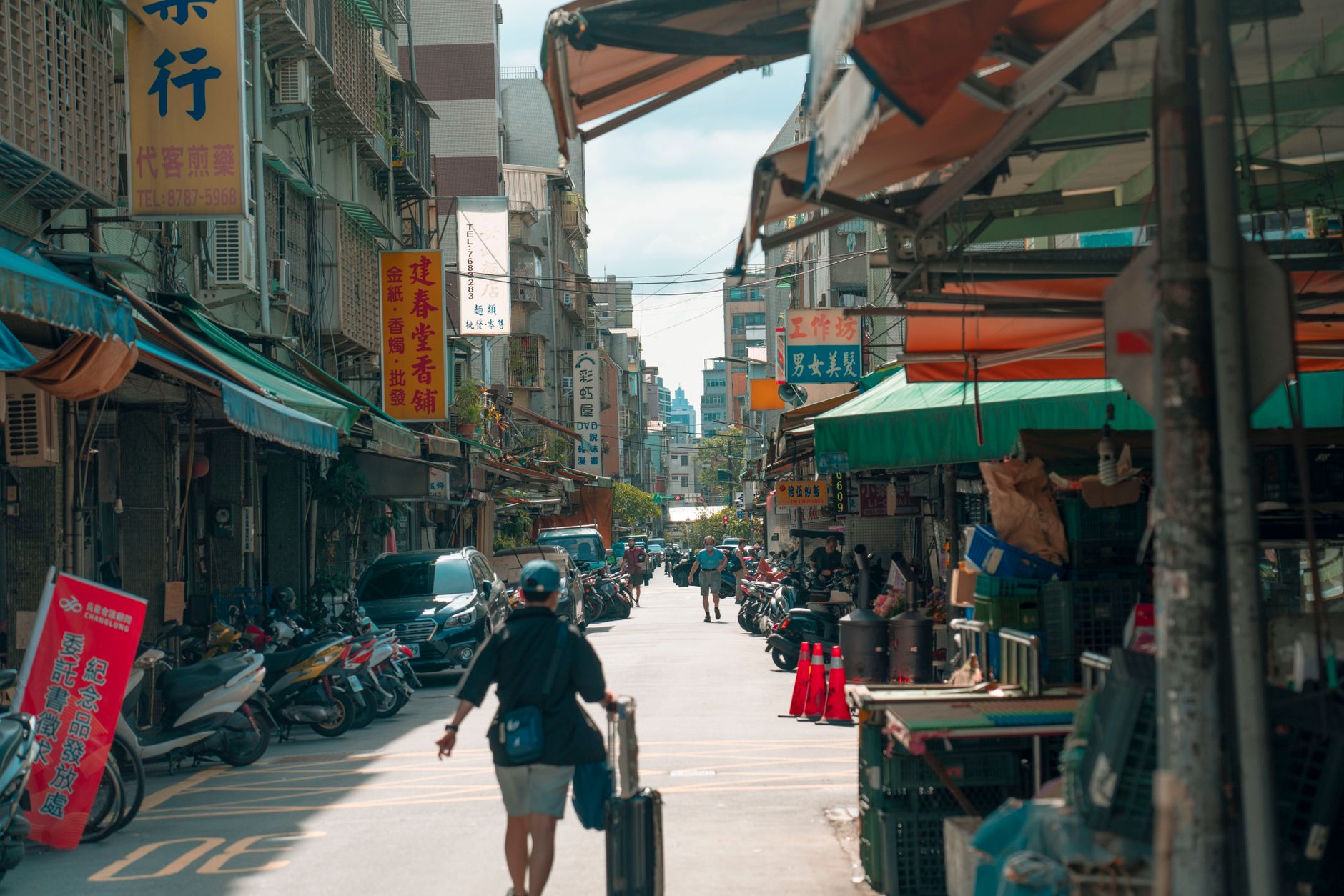 Vibrant street scene in Taipei’s Xinyi District, featuring shops, motorbikes, and pedestrians.